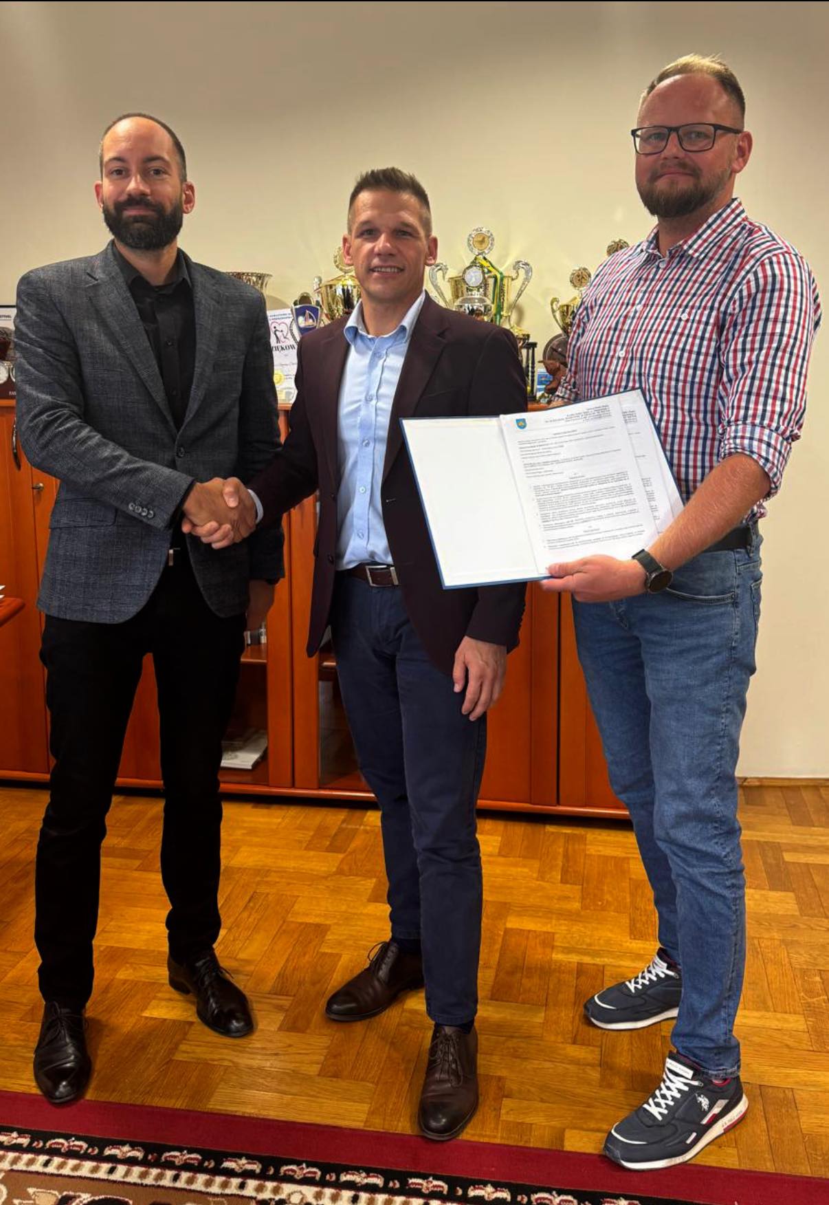 Trzej mężczyźni pozujacy do zdjęcia w pomieszczeniu