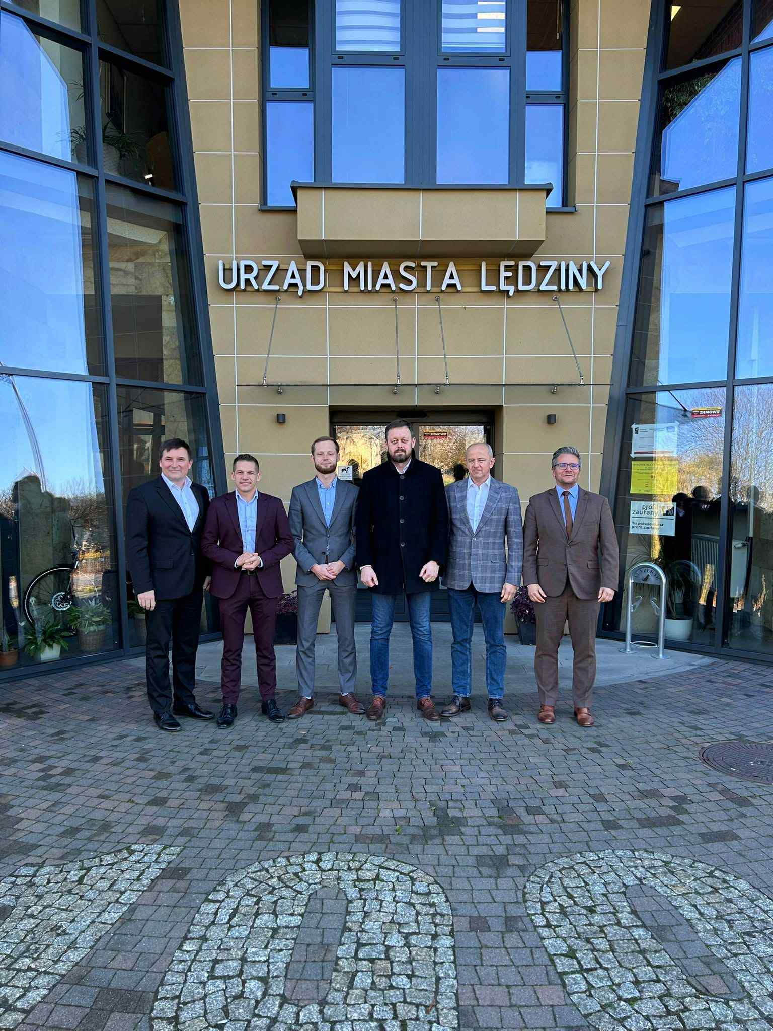 Mężczyżni stojący przed budynkiem ratusza w Lędzinach